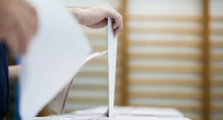hand inserting paper ballot into ballot box